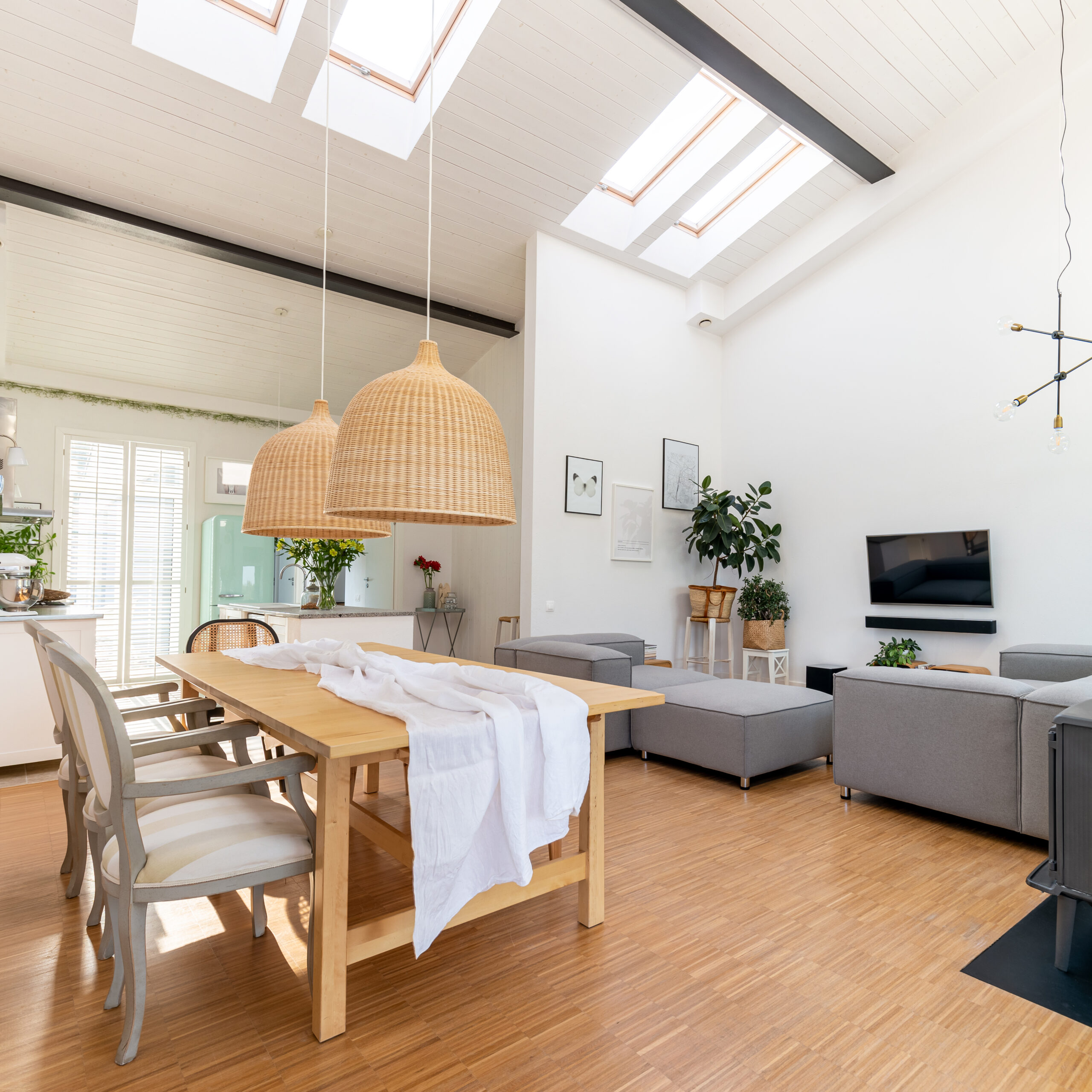 Open space living and dining room interior with flat tv, grey sofa and wooden table with trendy chairs